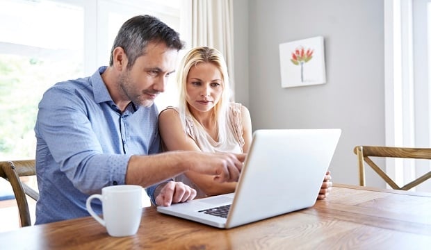 couple at desk reviewing finances on laptop